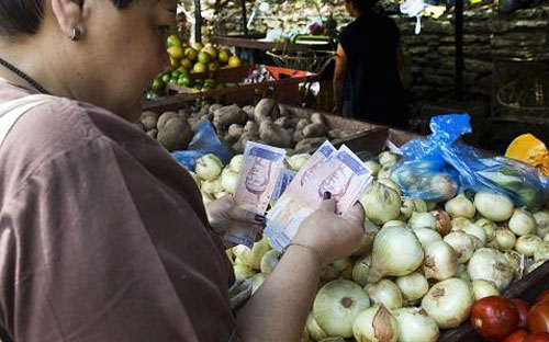 Một người phụ nữ Venezuela dùng đồng nội tệ để mua PG88 xổ số, casino, bóng đá trong một chợ ở Caracas ngày 1/10/2015 - Ảnh: Reuters.<br>