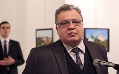 Đại sứ Nga ở Thổ Nhĩ Kỳ Andrei Karlov phát biểu khai mạc Triển lãm ảnh tại Thủ đô Ankara. Phía sau ông là tên sát thủ - Ảnh: AP.<br>