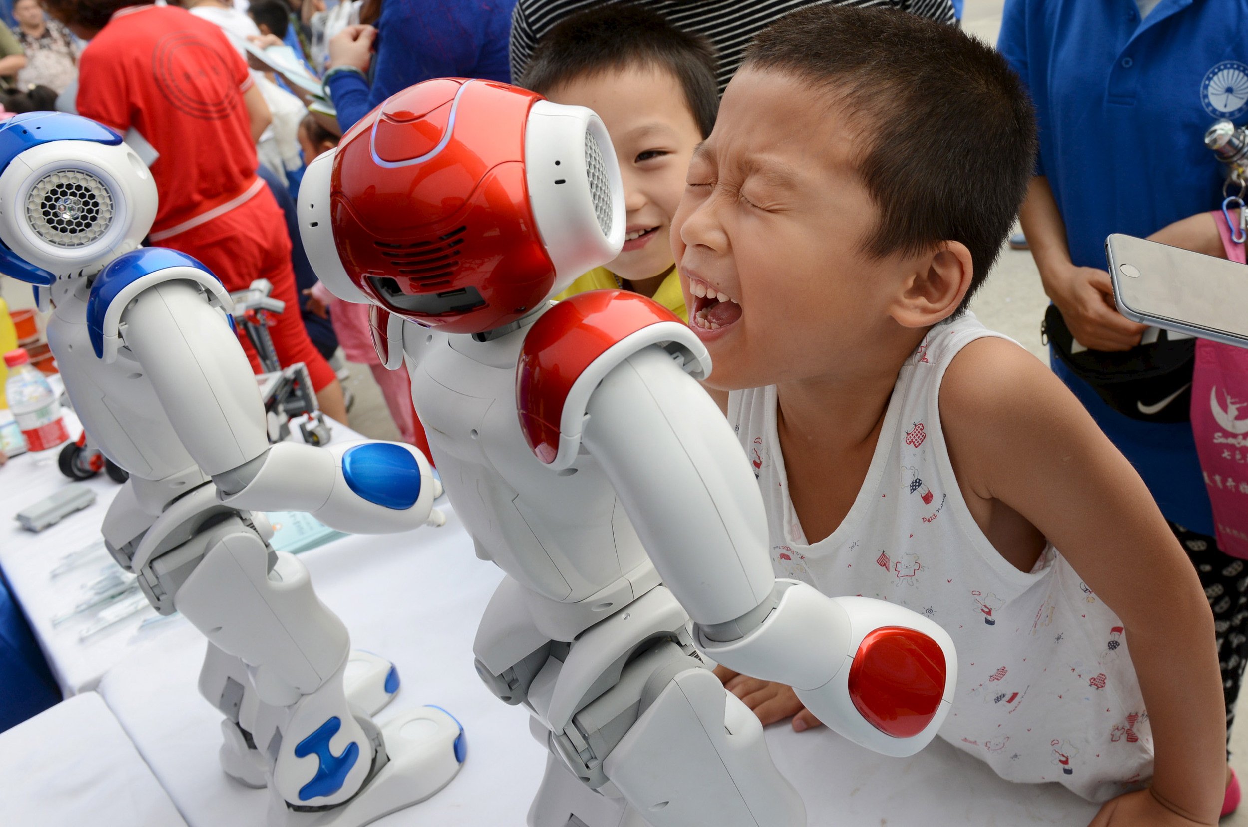 Những em bé đang nô đùa với robot trong một triển lãm ở Trung Quốc - Ảnh: Business Insider.<br>