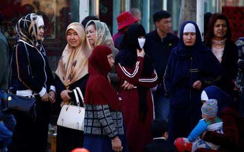 Phụ nữ người Duy Ngô Nhĩ đứng chờ xe bus ở Urumqi, thủ phủ Tân Cương, Trung Quốc - Ảnh: Reuters.<br>