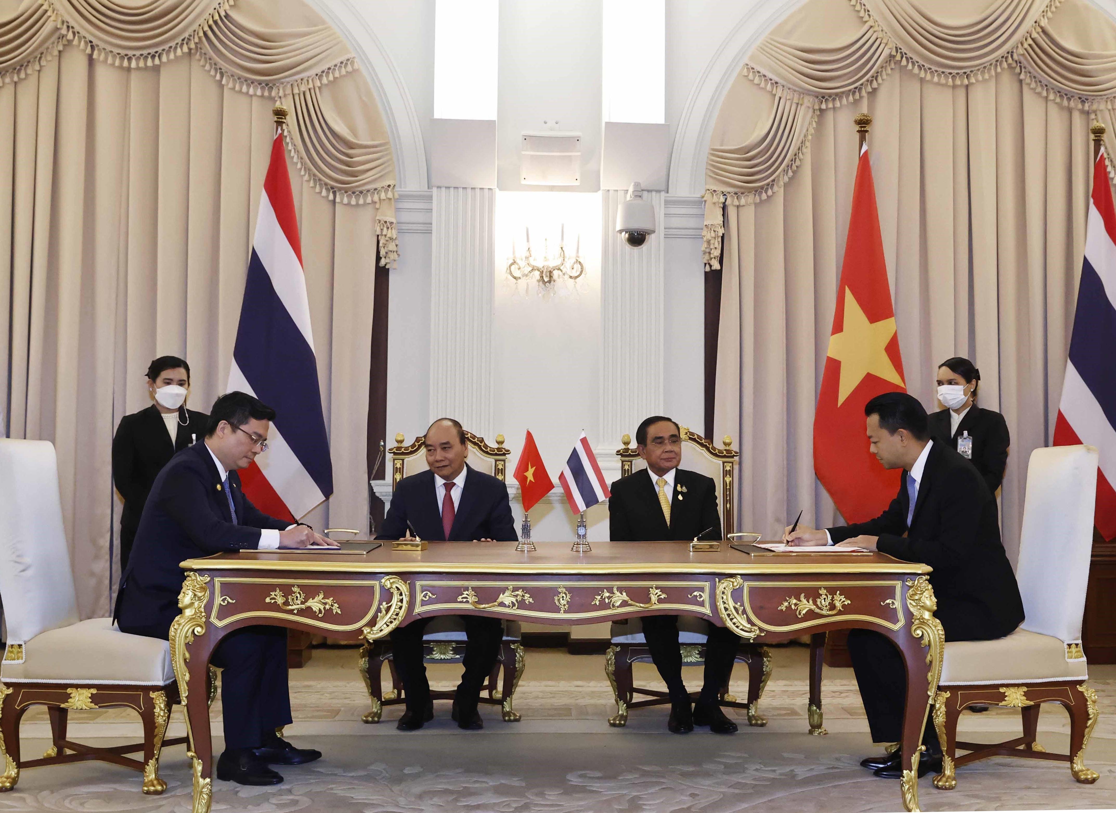 Đại diện Vietcombank, ông Nguyễn Thanh Tùng, Phó Tổng Giám đốc phụ trách Ban Điều hành (bên trái) và đại diện Eximbank Thái Lan, Ts. Rak Vorrakitpokatorn, Tổng Giám đốc (bên phải) ký kết thỏa thuận hợp tác trước sự chứng kiến của Chủ tịch nước Cộng hòa Xã hội Chủ nghĩa Việt Nam Nguyễn Xuân Phúc và Thủ tướng Thái Lan Prayuth Chan-ocha. Ảnh: TTXVN.