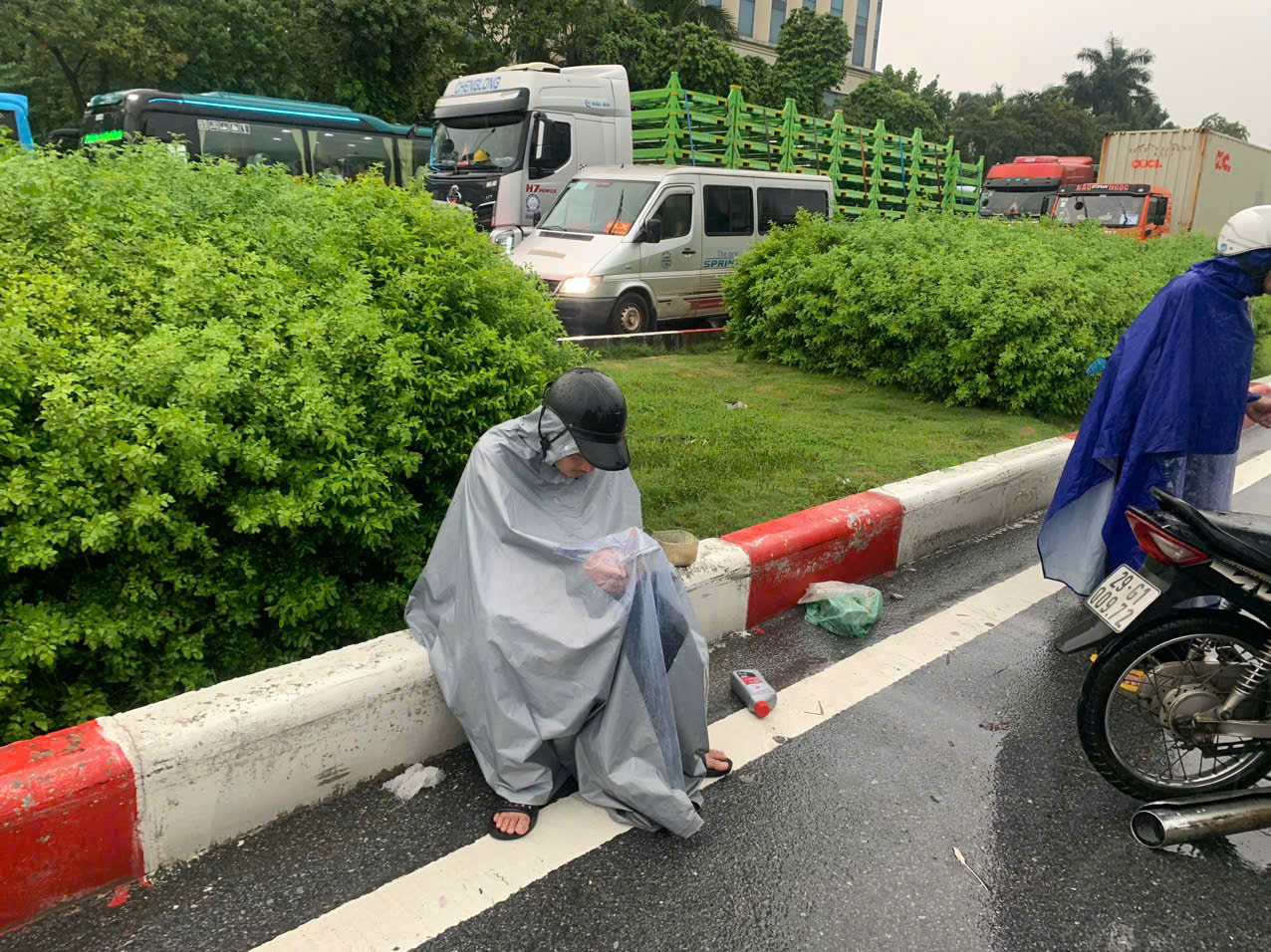 Có người chán nản ngồi giữa trời mưa lướt điện thoại để chờ sửa xe và nước rút...