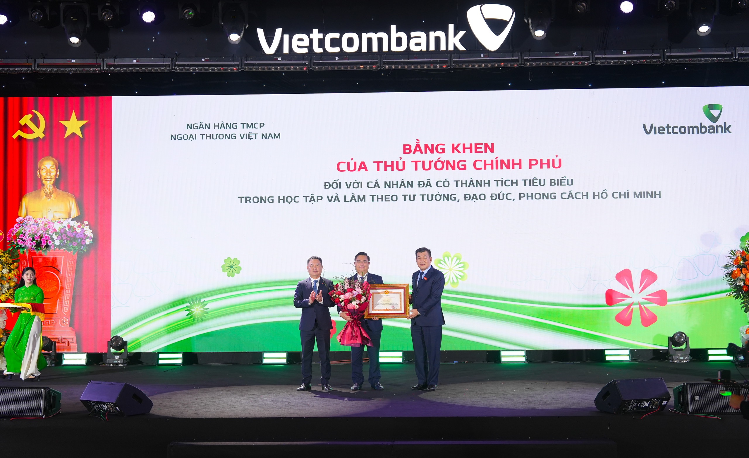 Đồng chí Nguyễn Đức Phong - Phó Bí thư chuyên trách Đảng ủy Chính phủ (bên phải) trao tặng bằng khen của Thủ tướng Chính phủ và đồng chí Nguyễn Ngọc Cảnh - Ủy viên BTV Đảng ủy, Phó Thống đốc NHNN (bên trái) tặng hoa chúc mừng đồng chí Nguyễn Thanh Tùng - Ủy viên BCH Đảng bộ Chính phủ, Bí thư Đảng ủy, Chủ tịch HĐQT Vietcombank vì đã có thành tích tiêu biểu trong học tập và làm theo tấm gương đạo đức, phong cách Hồ Chí Minh.