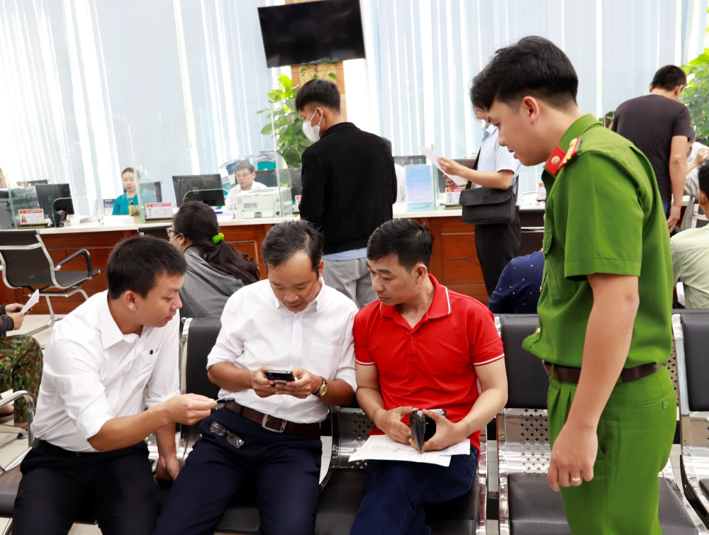 Cán bộ hướng dẫn người dân sử dụng dịch vụ công trực tuyến trên thiết bị điện tử.