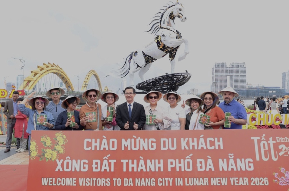 Phoa Giám đốc Sở Văn hóa, Thể thao và Du lịch Đà Nẵng Tán Văn Vương (người áo Vecton đứng giữa) chụp ảnh lưu niệm với khách quốc tế đến tham quan Cầu Rồng.